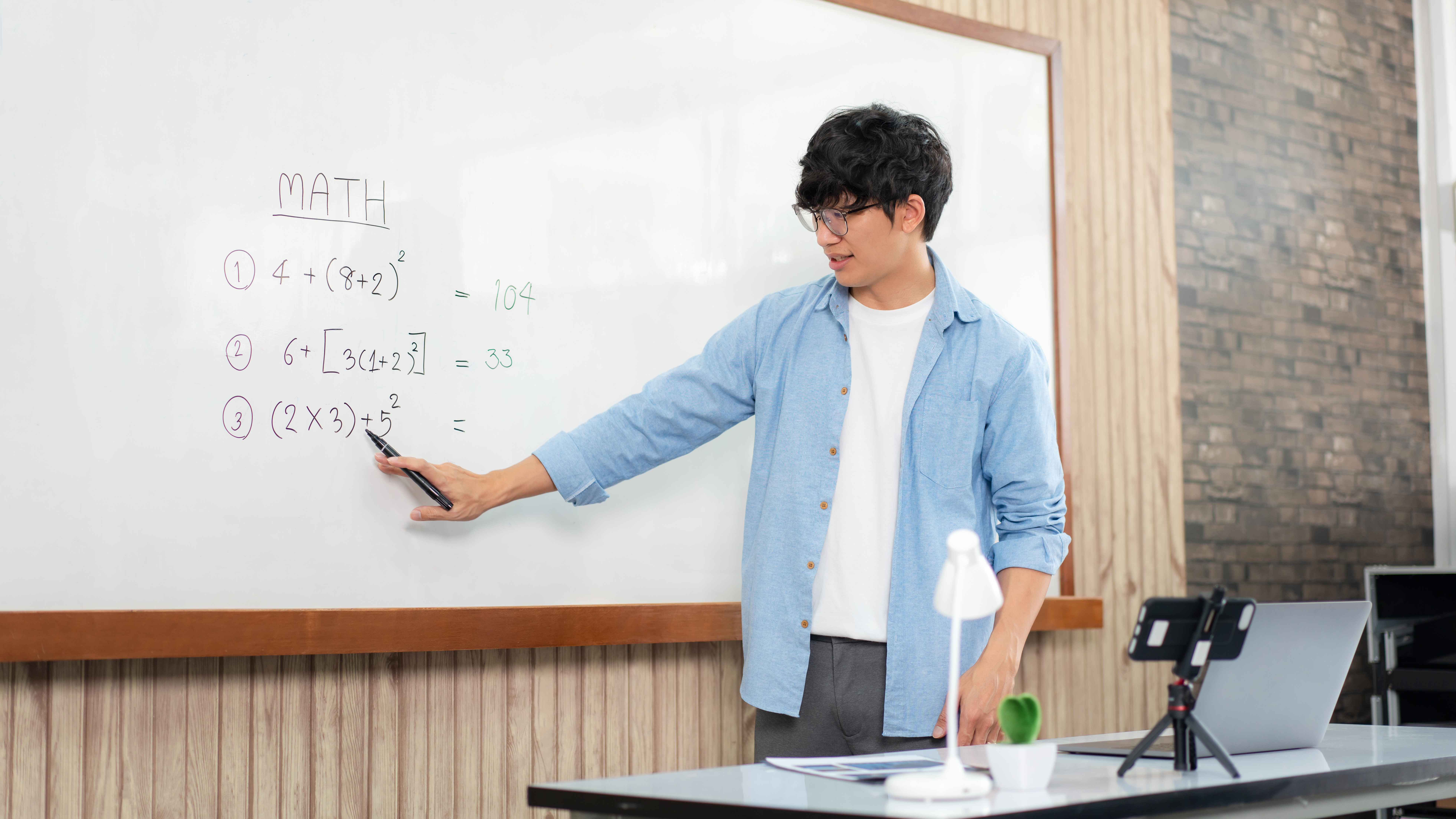 Male tutor standing in front of whiteboard and writing math equations